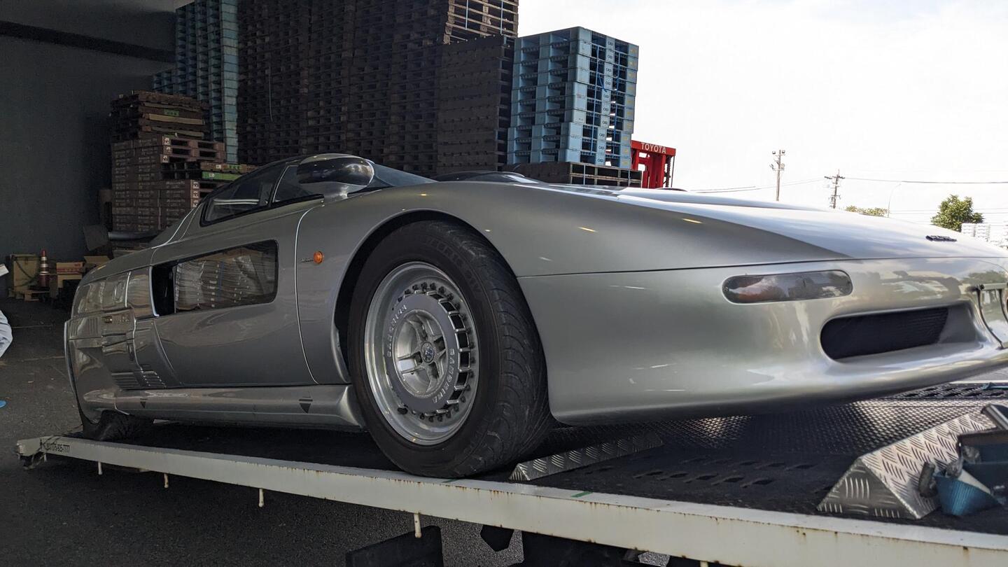 Aztec on a car transporter before departure from Japan, front three-quarter view
