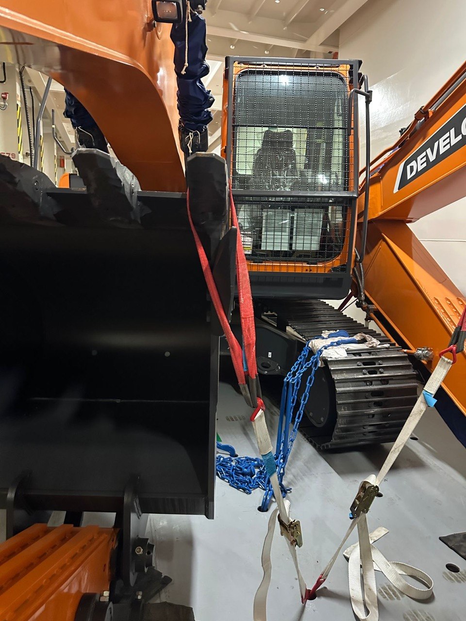 Chains and straps securing a tracked DEVELON excavator on deck