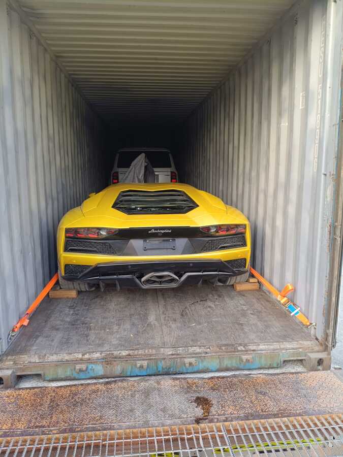 Dwa auta w jednym kontenerze: Aventador przy drzwiach i Toyota w głębi.