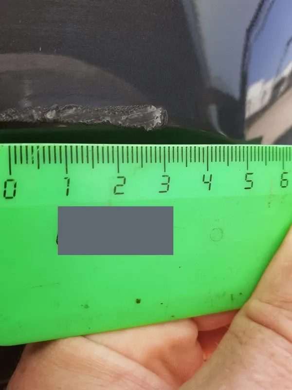 The same reported scratch photographed next to a ruler