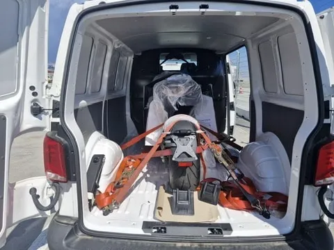 A motorcycle inside a compact van, with floor protection, a wheel stop and straps visible.