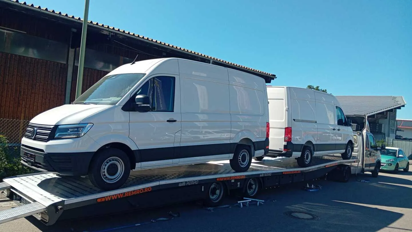 Two Volkswagen Crafter L3H3 vans on an open car transporter during the Germany to Bishkek project