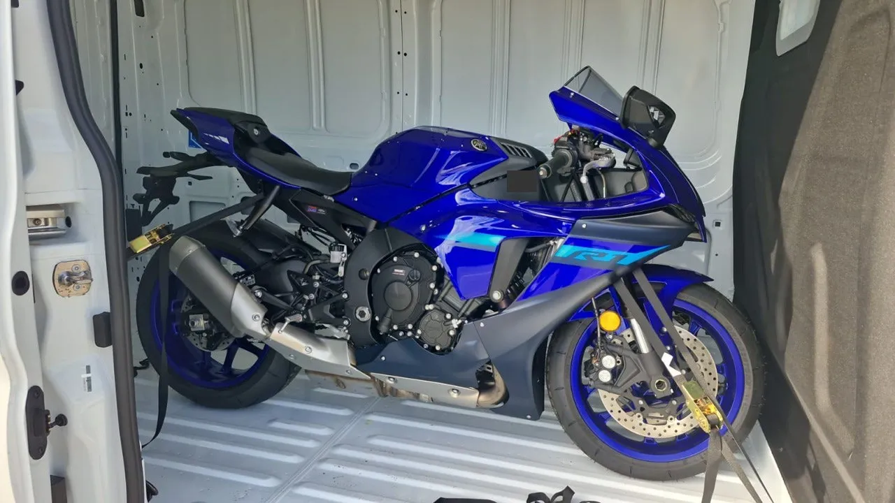 A Yamaha motorcycle inside a van, viewed through the side opening. One of the shipments in the series.